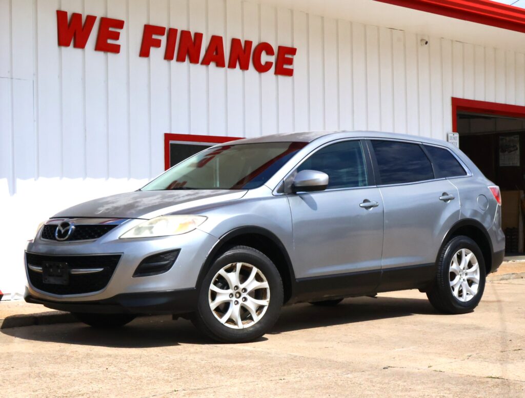 Silver SUV parked in front of a white building with a bold red 'WE FINANCE' sign