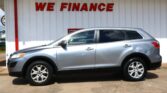 Silver SUV parked in front of a white wall with large red 'WE FINANCE' sign above.