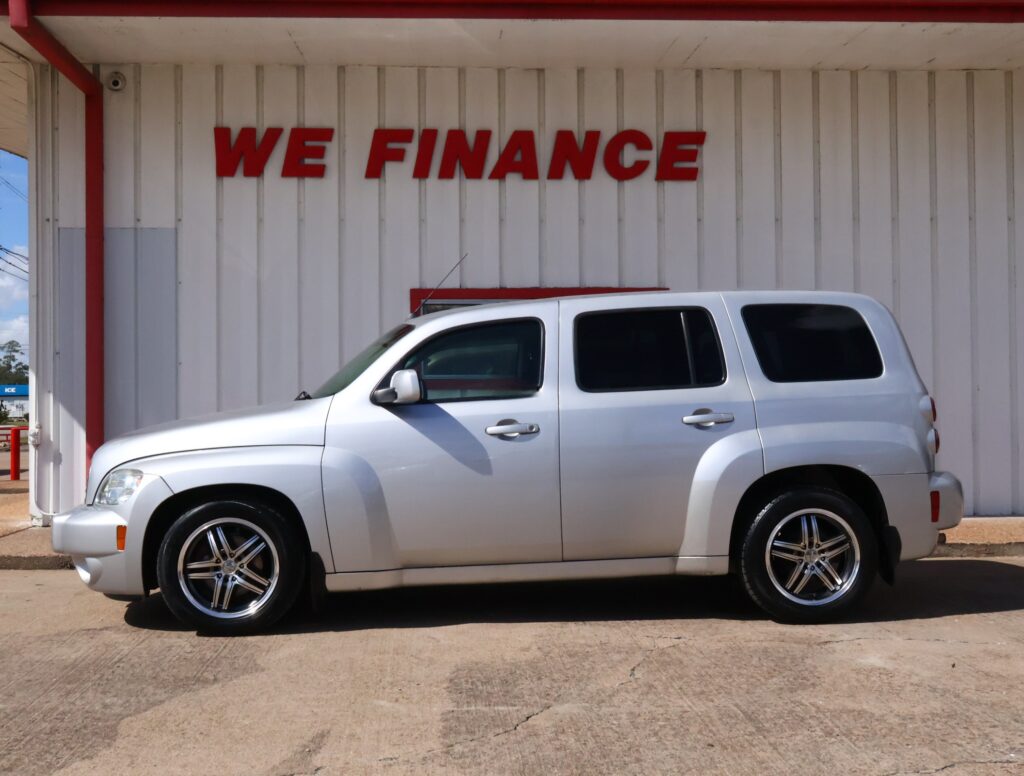 Silver SUV parked in front of a white building with bold red 'WE FINANCE' sign above.
