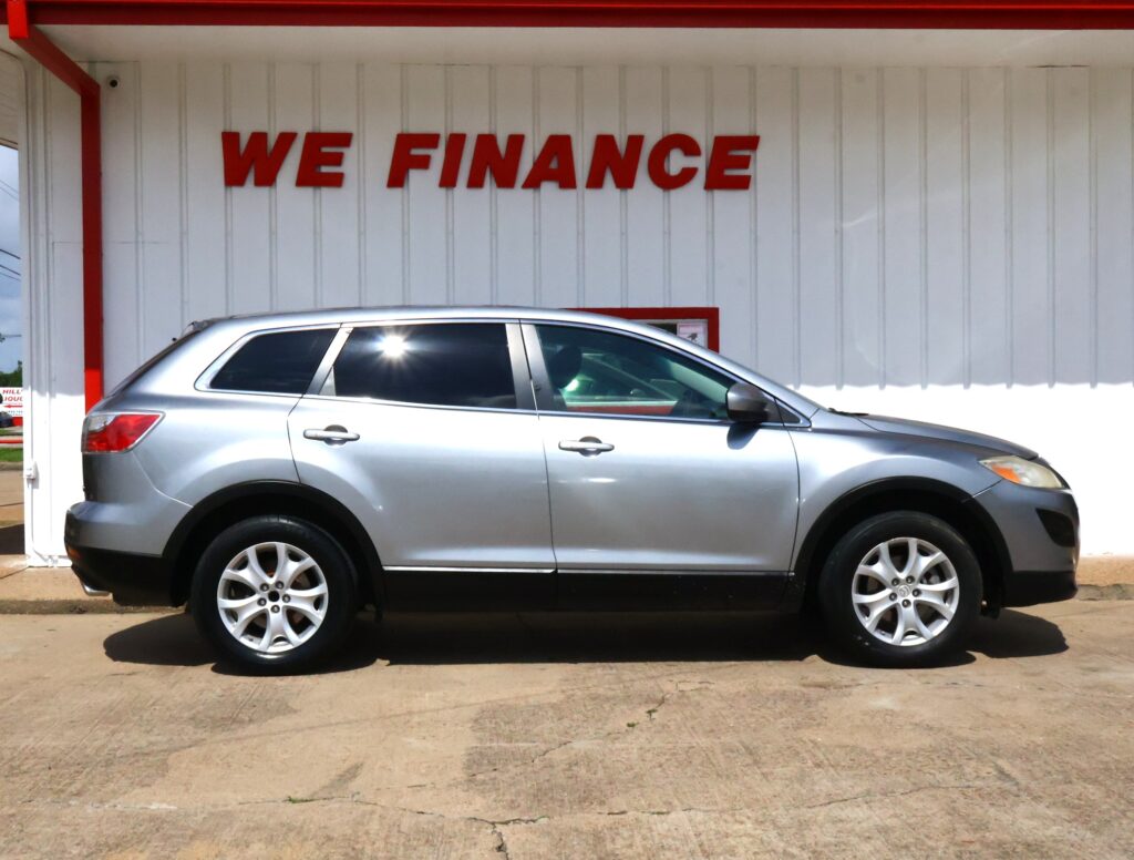 Silver SUV parked in front of a white wall with large red 'WE FINANCE' sign, likely at a car dealership.