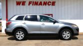 Silver SUV parked in front of a white wall with large red 'WE FINANCE' sign, likely at a car dealership.