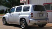 Silver Chevrolet SUV parked in a lot beside a white building with red trim and a Dillon Auto Sales sign in the background.
