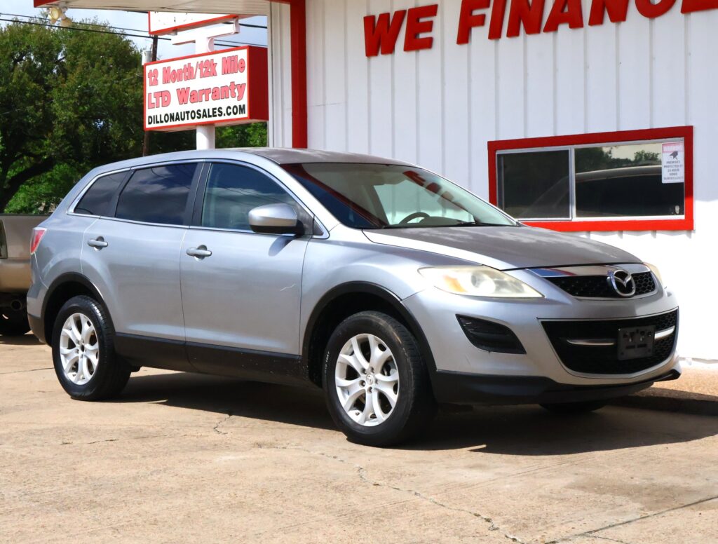 Silver SUV parked in front of a white building with red trim and large 'WE FINANCE' sign at a car dealership.