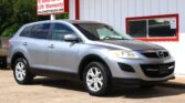 Silver SUV parked in front of a white building with red trim and large 'WE FINANCE' sign at a car dealership.