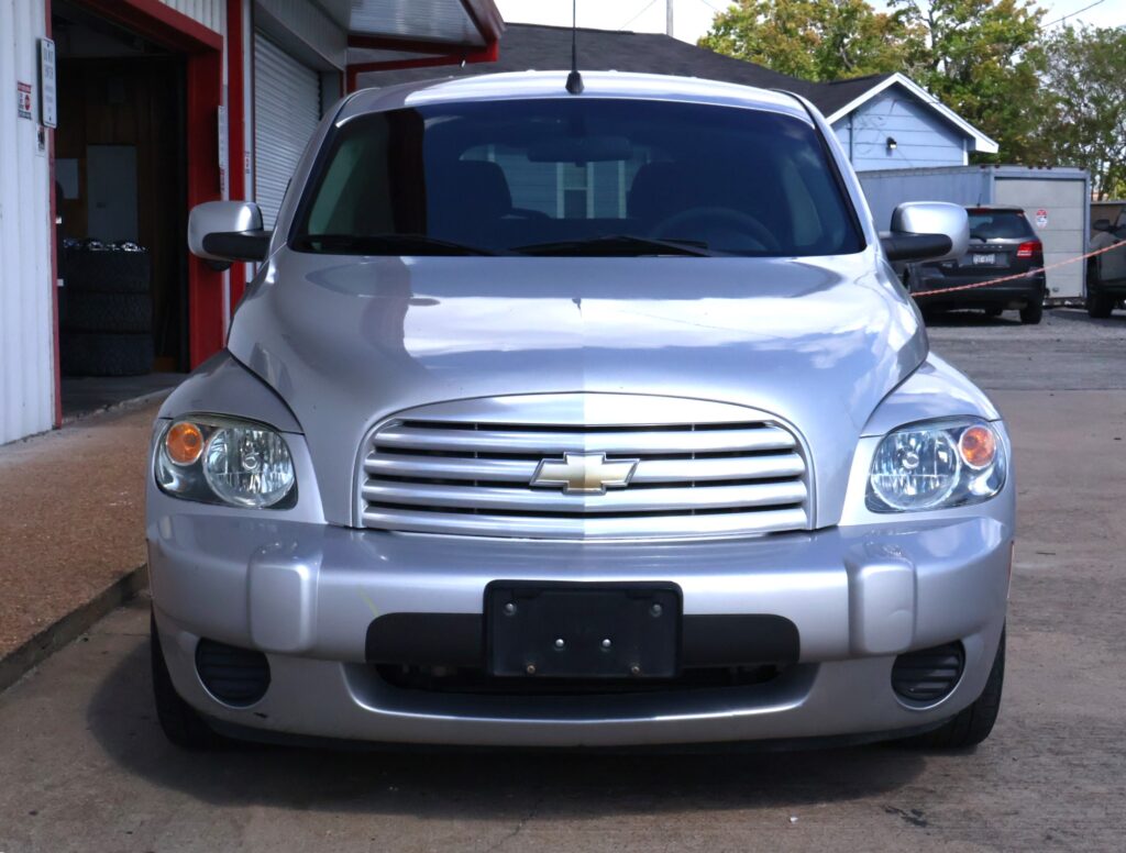 Front view of a silver Chevrolet SUV parked outdoors, showing the grille with the gold Chevrolet bowtie emblem and headlights.