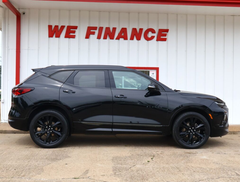 Black SUV parked in front of a white wall with red WE FINANCE lettering at a car lot.