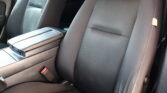 Dark gray car interior showing the two front seats with a center armrest between them and visible seat belts/console area.