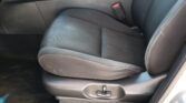Front passenger car seat with a visible red-release seat belt buckle against dark upholstery.