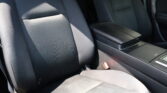 Dark fabric car seats inside a vehicle, with a center armrest/console and visible seat belts.