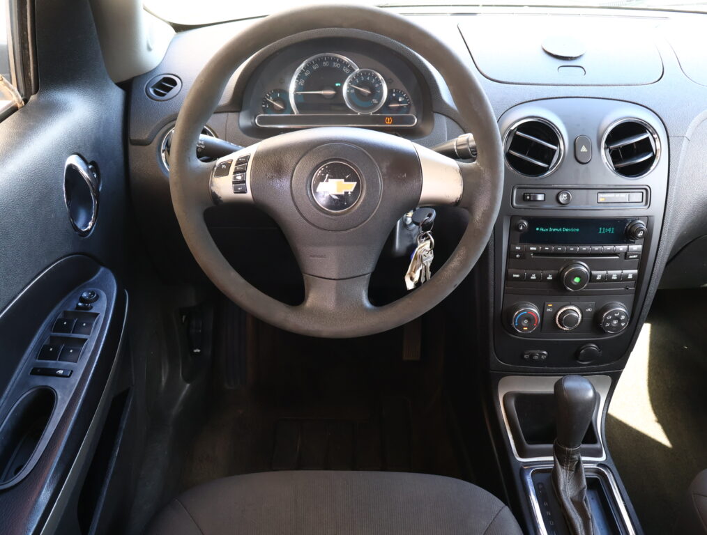 View of a car's interior focusing on the steering wheel, instrument cluster, and center console on the dashboard (Chevrolet).
