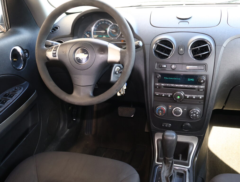 Front interior of a car showing the steering wheel, instrument cluster, and center console with radio and climate controls.