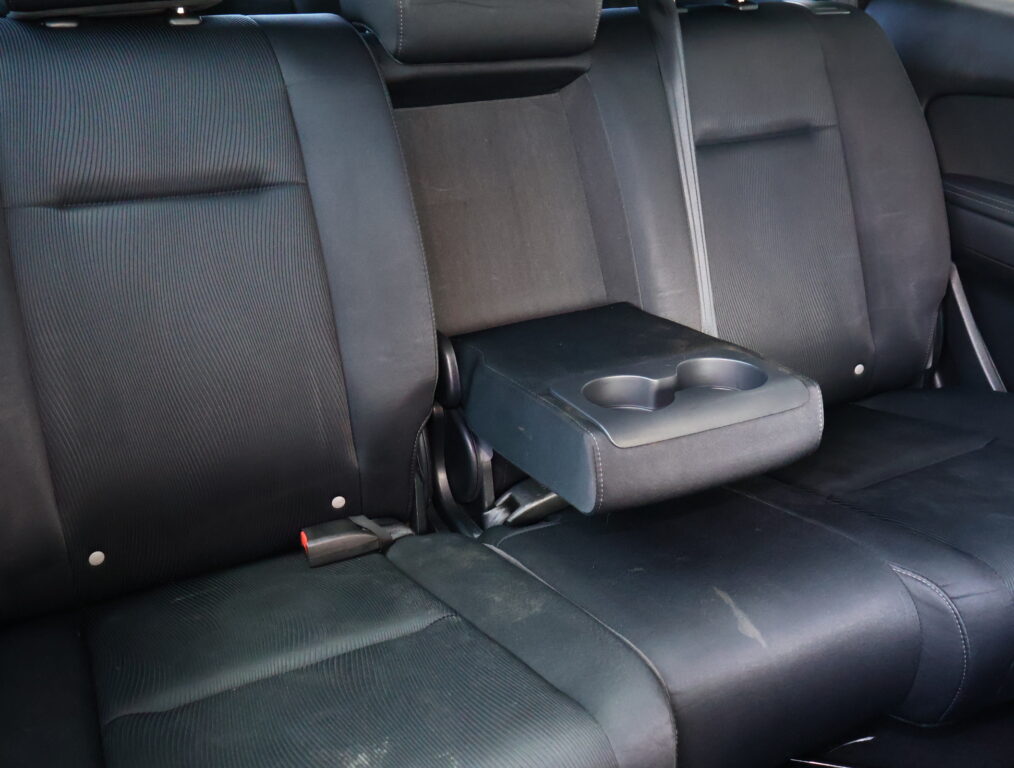 Backseat of a car with black fabric upholstery and a center armrest housing two cup holders