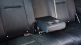 Backseat of a car with black fabric upholstery and a center armrest housing two cup holders