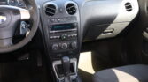Interior of a car showing the steering wheel on the left and a center console with two round air vents, hazard button, and radio beneath it.