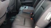 Rear car seats with a fold-down center armrest housing two cupholders and black upholstery.