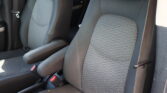 Front car seats with gray patterned fabric and visible seat belts; center console between seats partially visible.