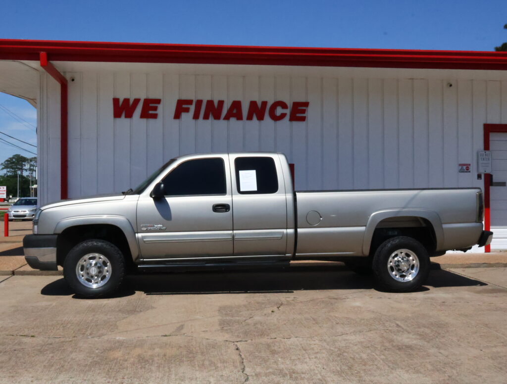 White pickup truck parked in front of a white building with a bold red 'WE FINANCE' sign above it.