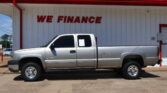 White pickup truck parked in front of a white building with a bold red 'WE FINANCE' sign above it.