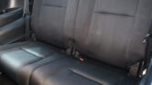 Back seat of a dark gray car with three-seat bench, visible seat belts and headrests, interior door panel nearby.
