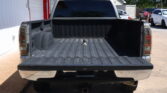 Rear view of a pickup truck with the tailgate down and empty bed in a parking lot