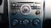 Center console of a car with a radio and climate controls: circular volume knob surrounded by buttons and preset keys on the dashboard.