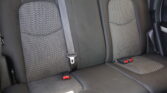 Back seat of a car with two patterned fabric cushions and visible seat belts, including red buckle tips on either side.