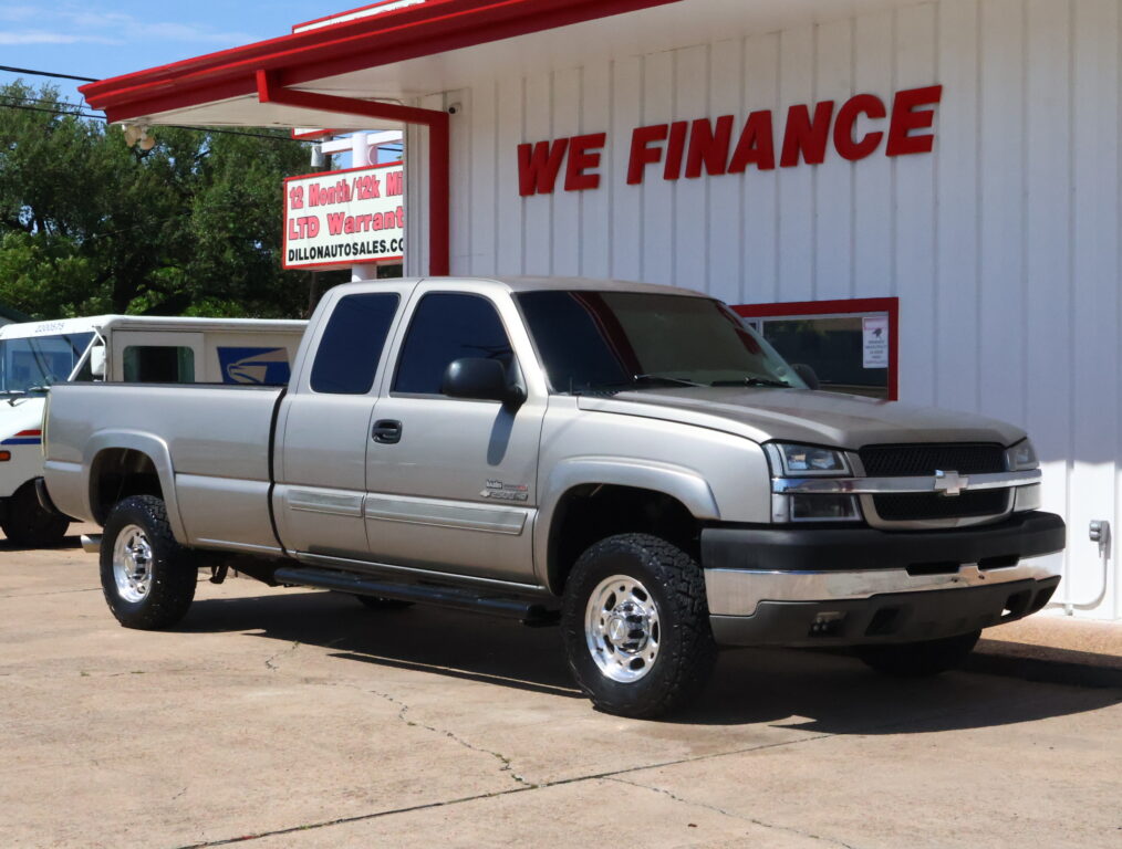 White pickup truck parked in front of a white building with red trim and a large 'WE FINANCE' sign behind.