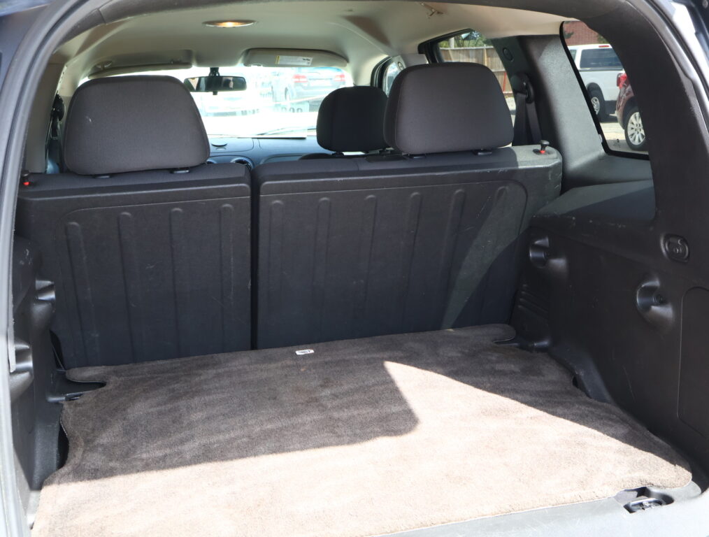 Rear cargo area of a dark SUV with third-row seats up and minimal clutter, showing a spacious trunk from the hatch opening.