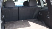 Rear cargo area of a dark SUV with third-row seats up and minimal clutter, showing a spacious trunk from the hatch opening.
