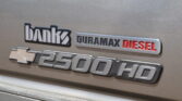 Chevrolet truck tailgate badges including a black-and-white logo and a 'DURAMAX DIESEL' badge on a metallic grey surface.