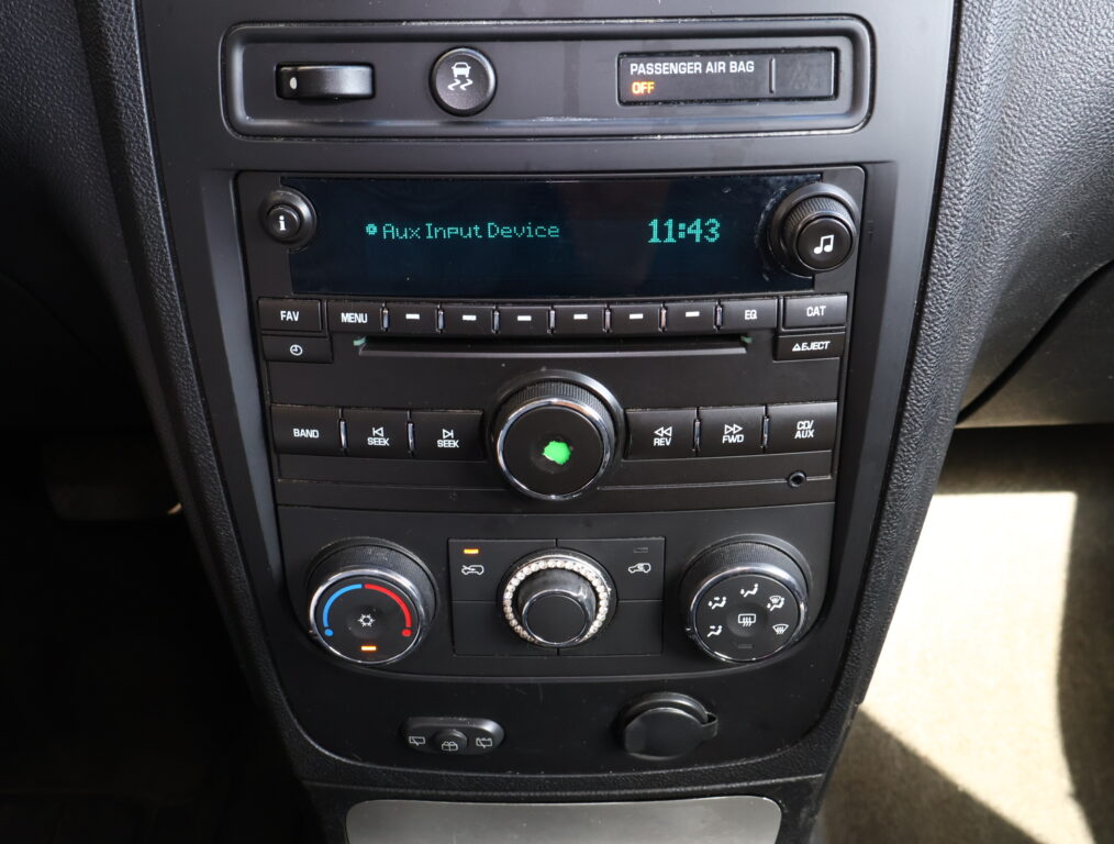 Car stereo display showing 'Aux Input Device' and the time 11:43, with knobs on both sides of the unit and climate controls below