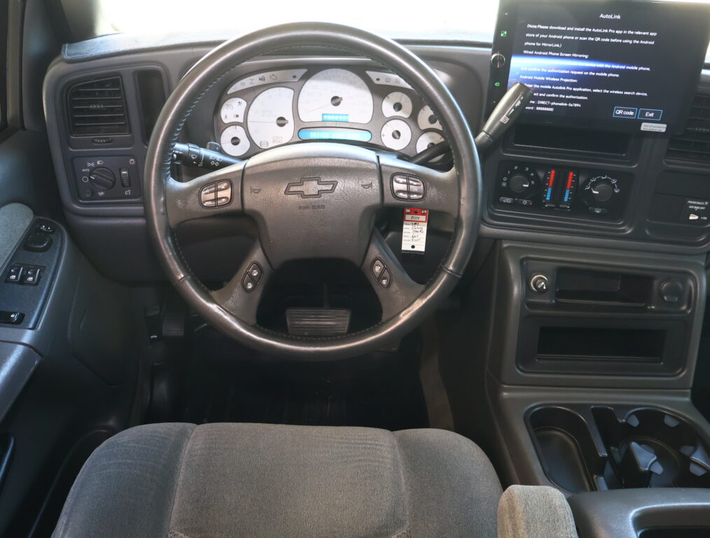 Driver's seat view of a pickup interior: steering wheel, analog gauge cluster, and a large infotainment touchscreen to the right.
