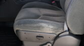 Front passenger seat in a dark gray car interior with visible seat adjustment lever and red seat belt buckle nearby.