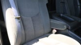 Gray cloth car seats with visible seat belts and a center armrest, showing interior of a vehicle.