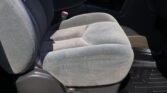 Gray cloth car seat with a red seatbelt buckle between the seat and center console in a vehicle interior.