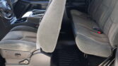 Interior of a dark gray pickup truck showing front captain chairs and a gray rear bench seat in fabric upholstery