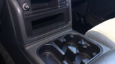Center console of a car showing cup holders, a small storage pocket, and a 12V power outlet next to a front seat area