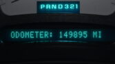Close-up of a car dashboard gear indicator showing PRND321 lit in teal, indicating current shift positions