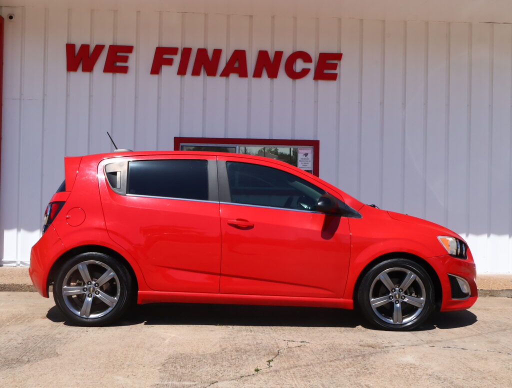 Red hatchback parked in front of a white wall with the bold red 'WE FINANCE' sign above it.