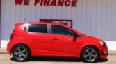 Red hatchback parked in front of a white wall with the bold red 'WE FINANCE' sign above it.