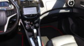 Front interior of a car showing steering wheel, center touchscreen, climate controls, and gear shifter with black and silver finish.
