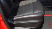 Front passenger seat in black leather with red contrast stitching and visible seat belt latch.
