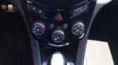 Close-up of a car's center console: hazard light button, lock controls, and climate control dials in a glossy black panel.