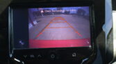 Rearview camera display with orange guide lines and the warning: 'Check Surroundings For Safety' (used to assist backing up).