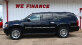 Black Chevrolet Suburban LTZ SUV parked in front of a white building with a red WE FINANCE sign above it