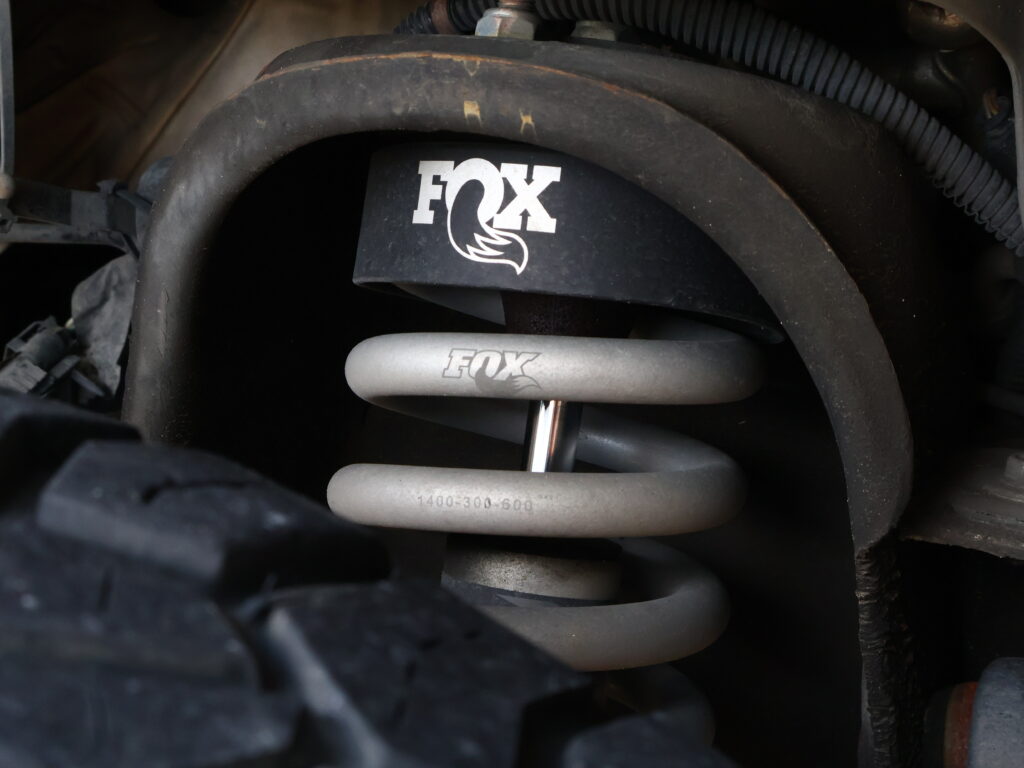 Close-up of a FOX-branded suspension coilover inside a vehicle's wheel well.