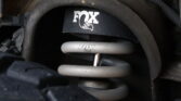 Close-up of a FOX-branded suspension coilover inside a vehicle's wheel well.