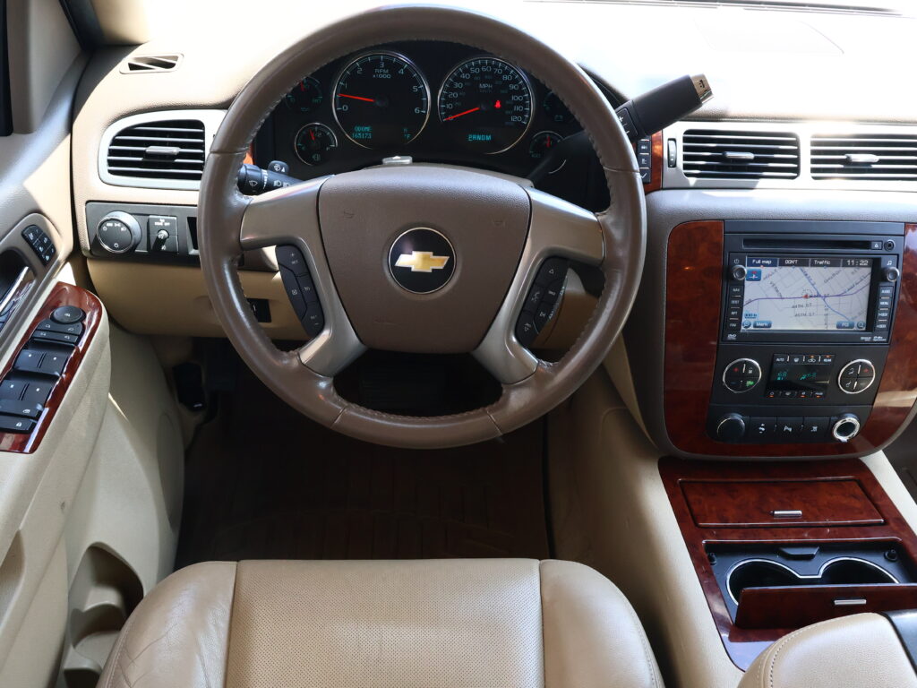Beige car interior focusing on the leather steering wheel, instrument cluster, and map navigation screen on the dash.