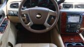 Beige car interior focusing on the leather steering wheel, instrument cluster, and map navigation screen on the dash.