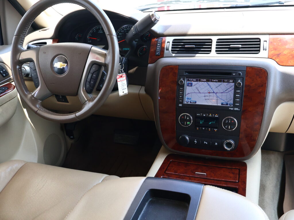 Inside view of a beige car cabin showing the steering wheel, wood-grain trim, and a built-in navigation/display screen.